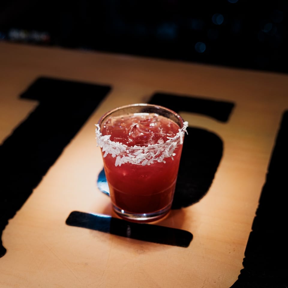 Red cocktail with a coconut-flake rim on the Saloon 151 bar.