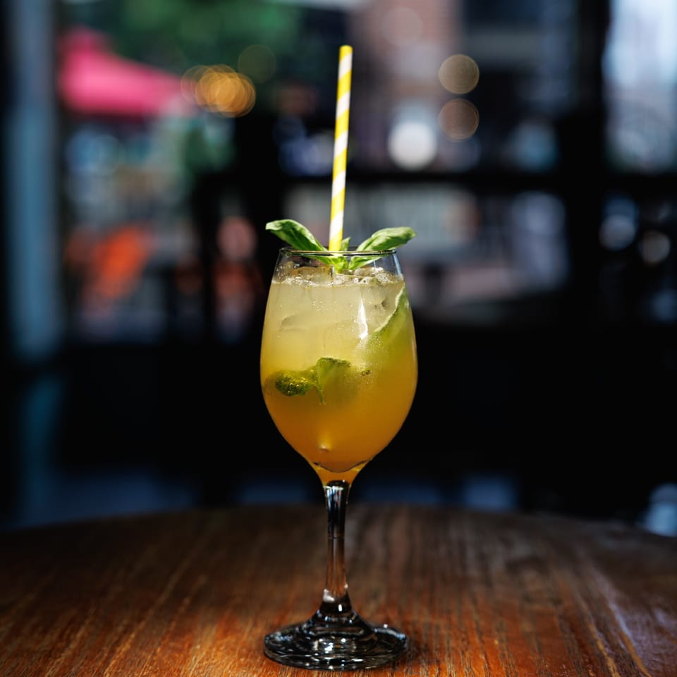 Golden citrus cocktail with fresh herbs at the bar.