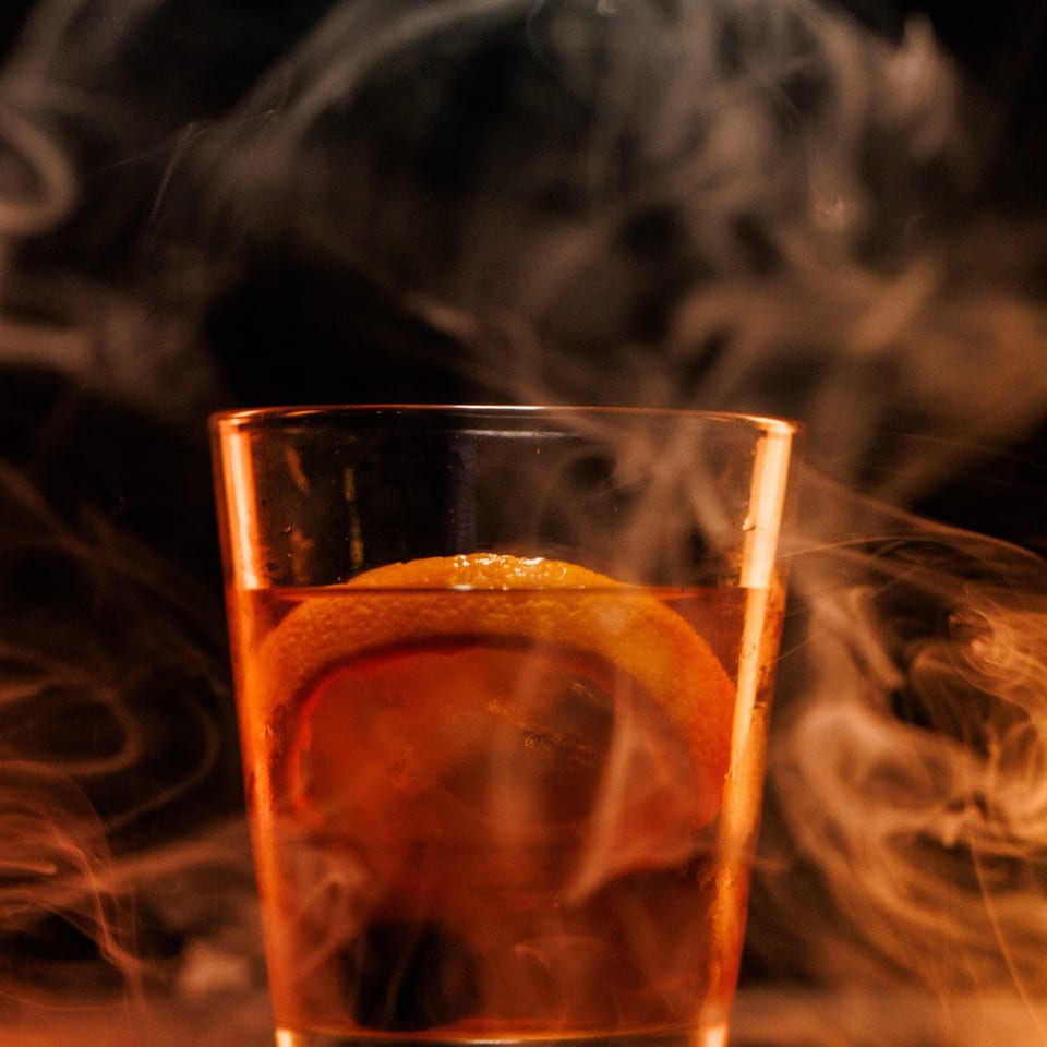 Smoked whiskey cocktail with orange peel.