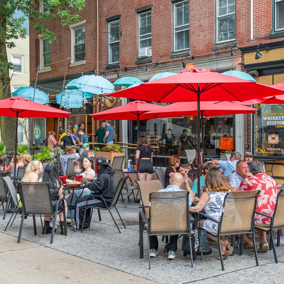 Guests dining on the patio beneath red umbrellas.