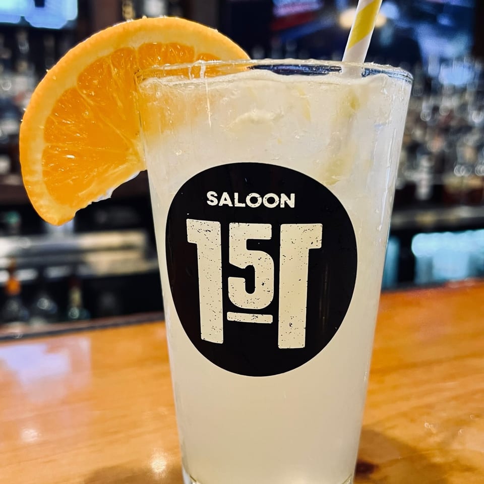 Orange-garnished drink in a Saloon 151 glass.
