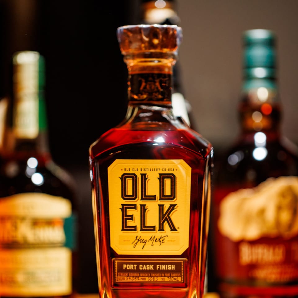 Old Elk whiskey bottle with the whiskey selection behind it.